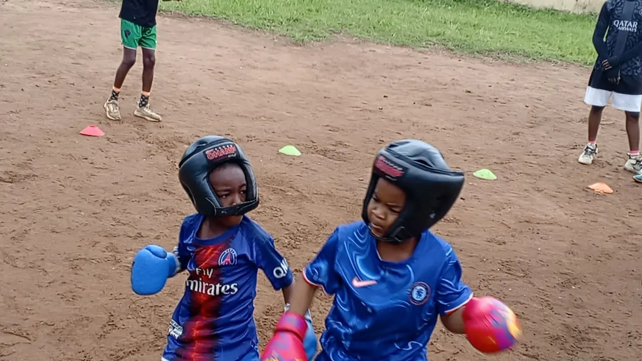 Two small kids in headgear and gloves facing each other