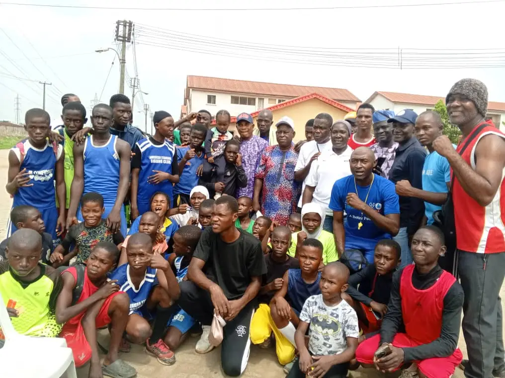 A large group of young boxers, coaches and families gathered together outdoors
