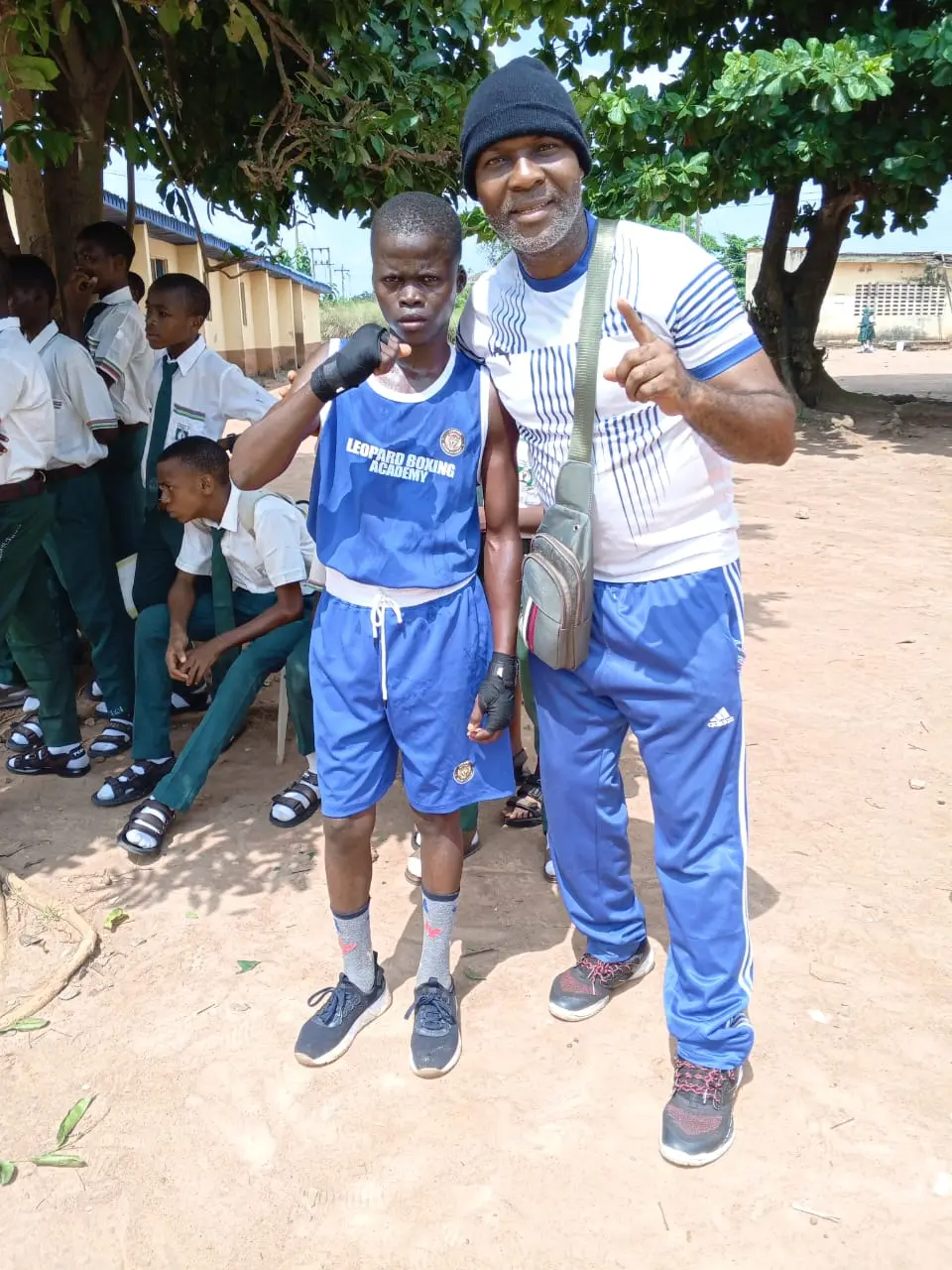 A coach beside a young boxer in a Leopard Boxing Academy vest