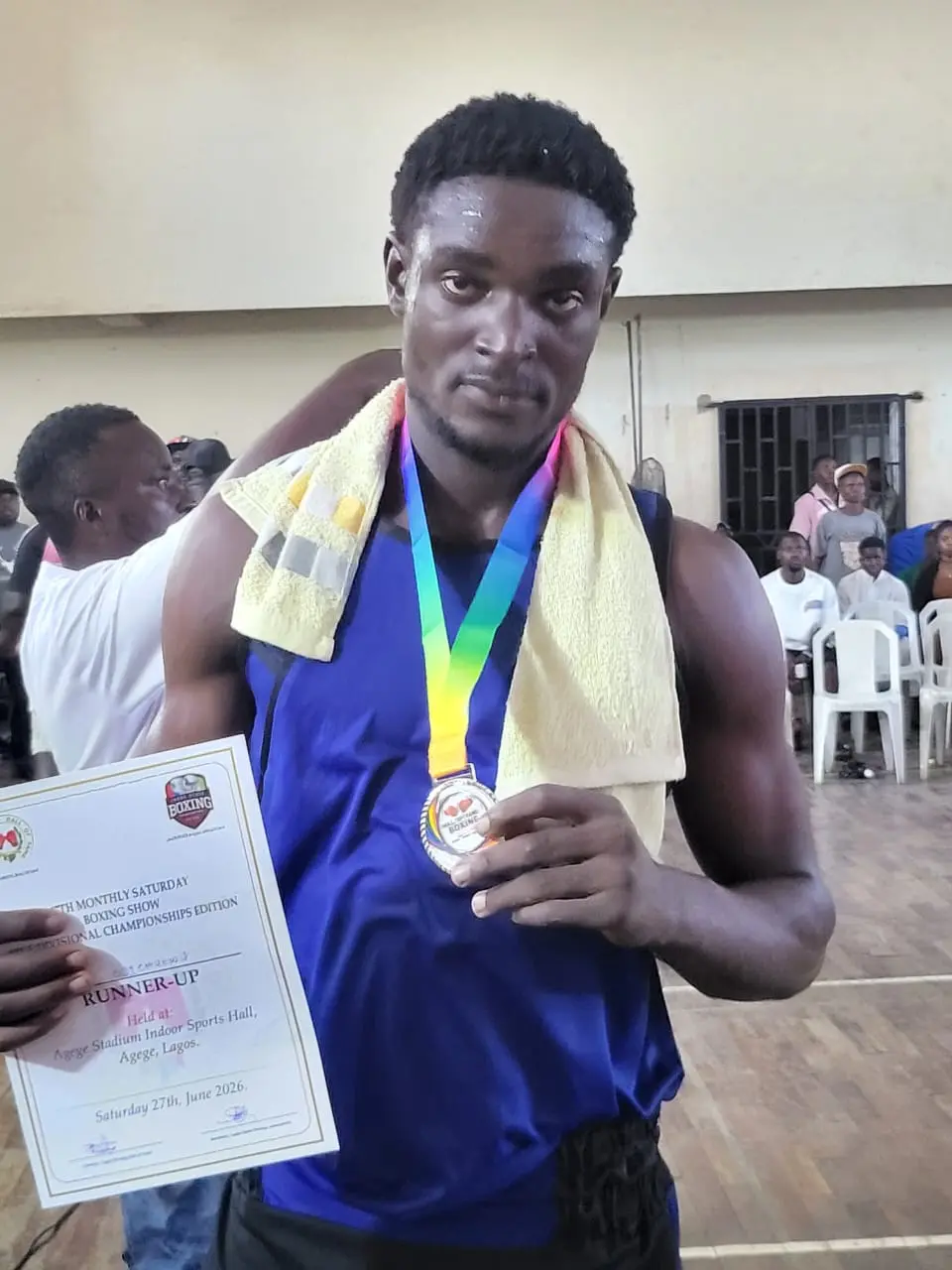 A young boxer smiling with a medal and certificate